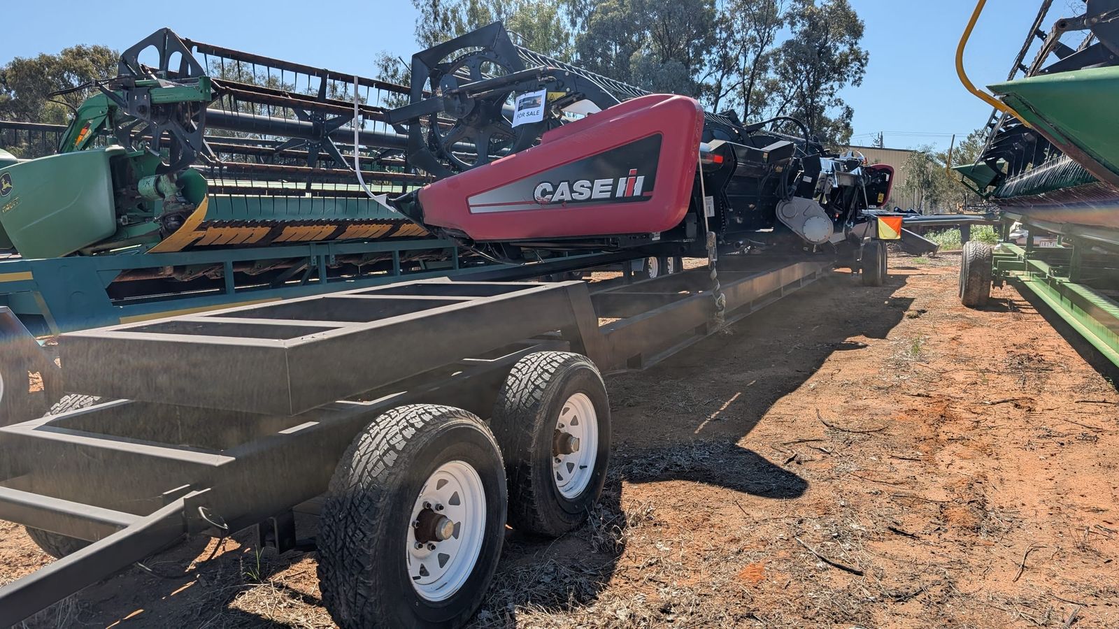 MacDon D60 40ft draper front beside its header trailer, end view showing the tandem axles