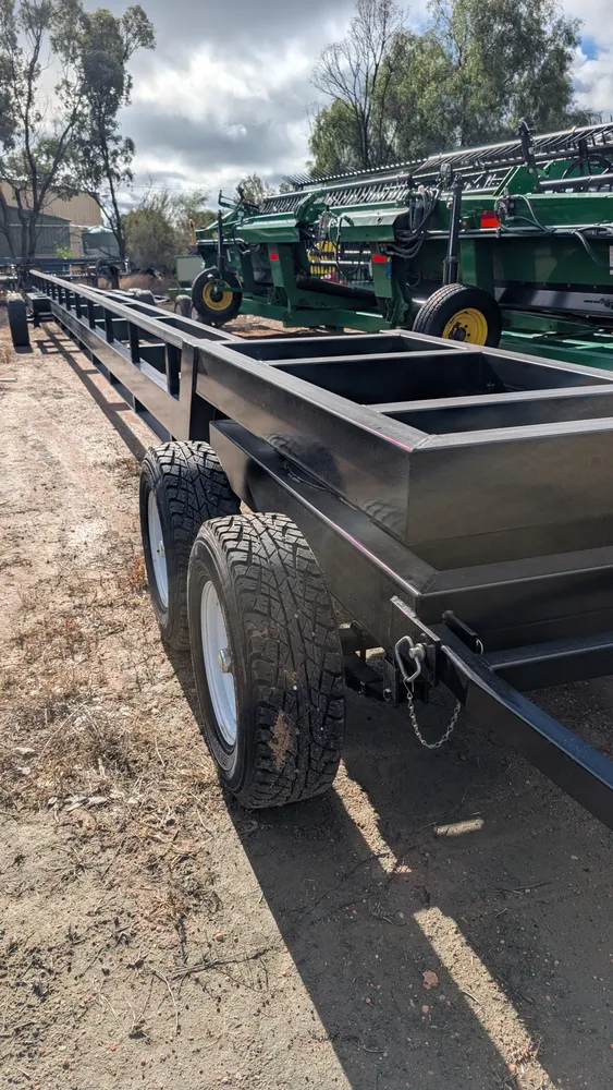 New comb trailer in the HFR yard at Swan Hill, drawbar and tandem axle in the foreground, John Deere fronts behind